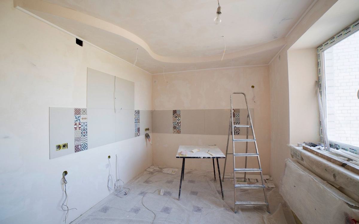 Freshly plastered room with bare walls, a ladder and dust sheets down